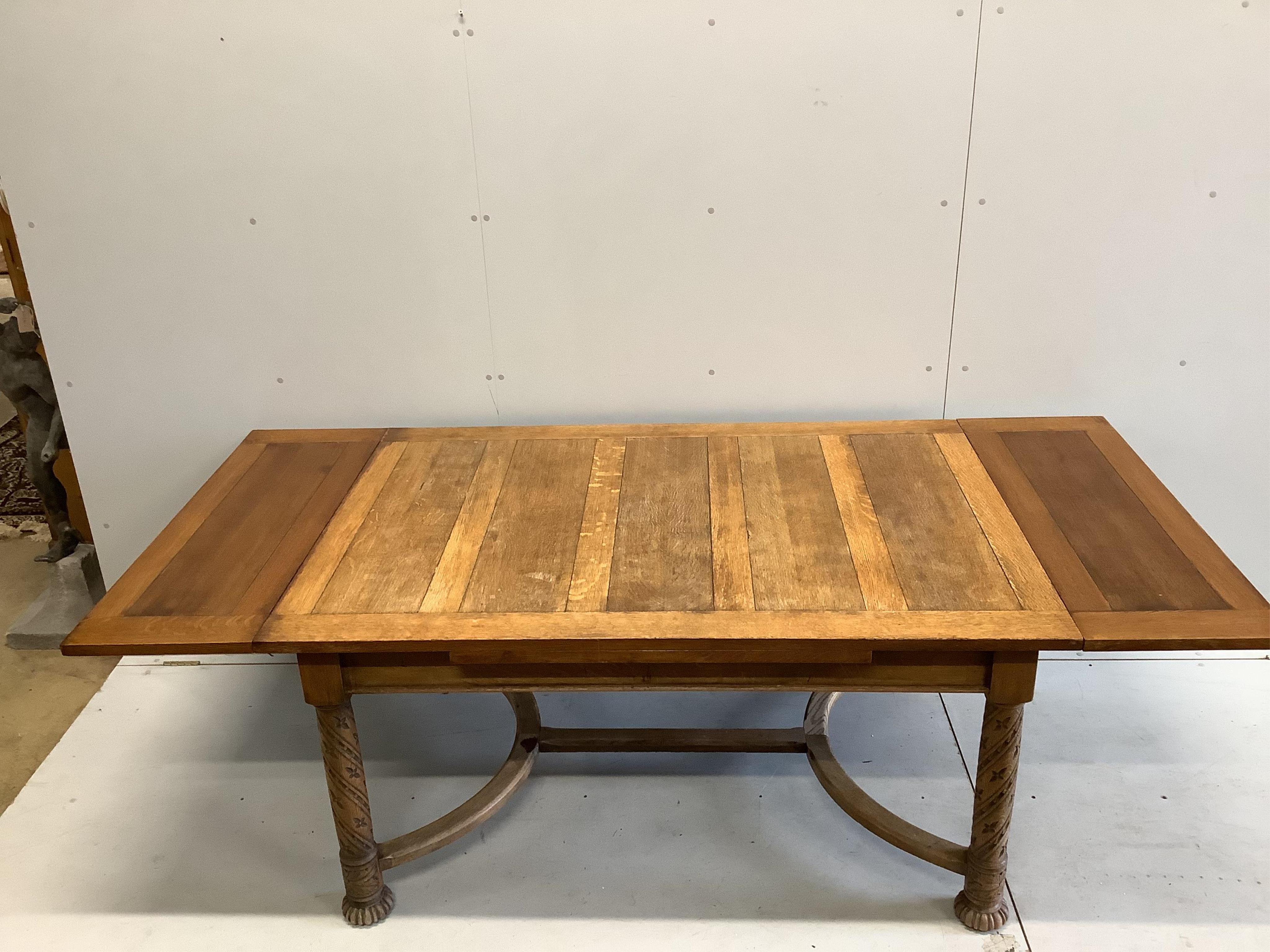 An early 20th century golden oak draw leaf dining table on carved underframe, width 153cm, 227cm extended, depth 106cm, height 76cm. Condition - fair